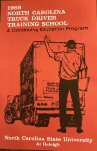 The 1968 cover of the Truck Driving School — depicting a monocrhome drawing of a man directing a truck in the process of backing up, set against a bold red background