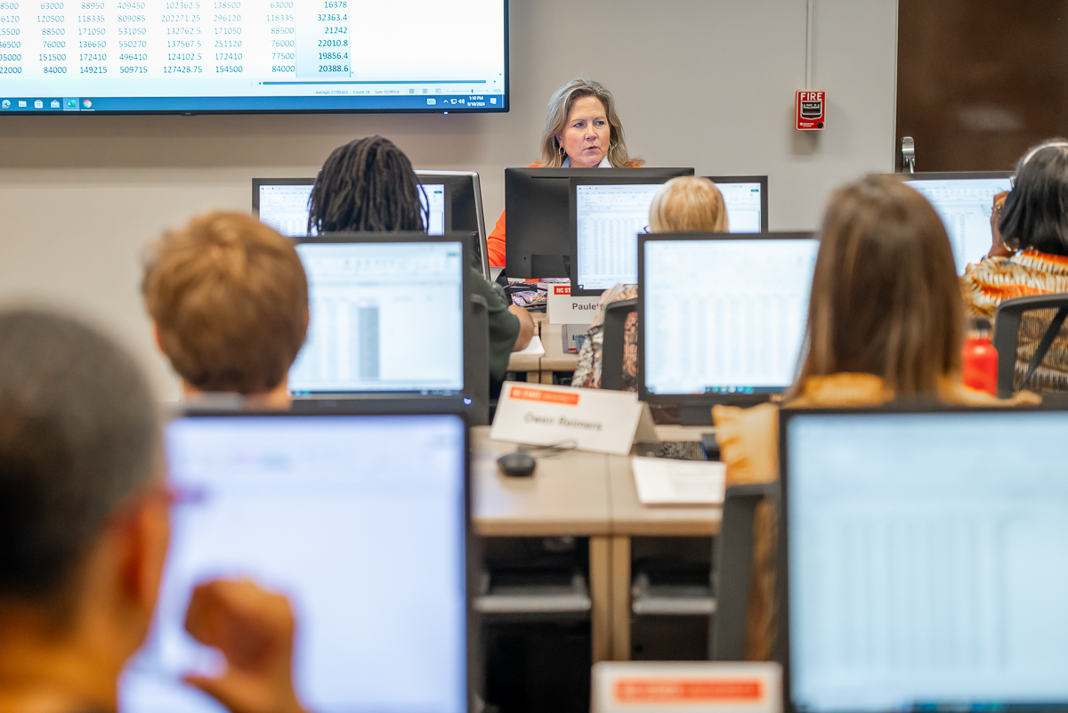 An instructor speaks to a room full of lifelong learners seated at computers