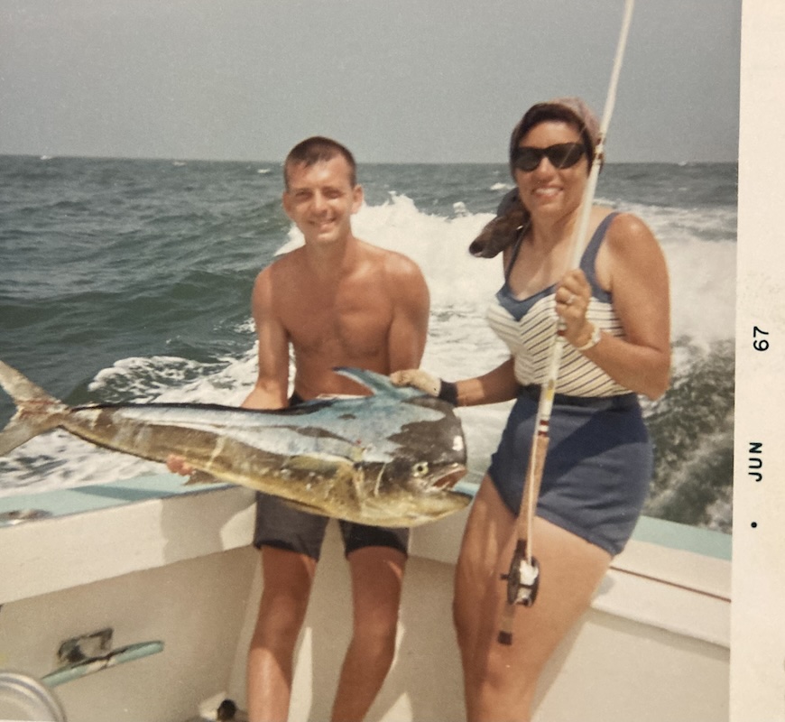 two participants sitting on the rear of the fishing boat, showing the large fish they caught