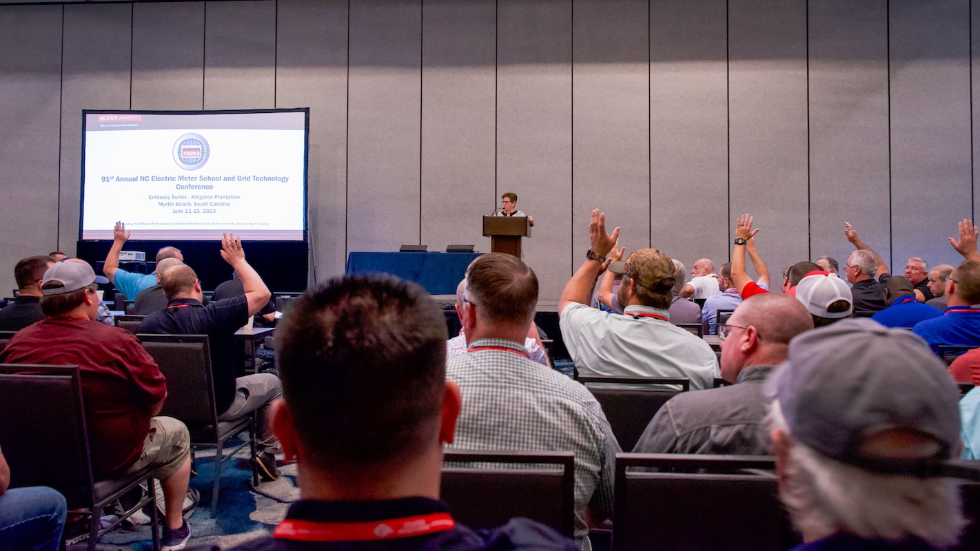 Meter school attendees sit in rows of chairs while a presenter speaks next to a screen