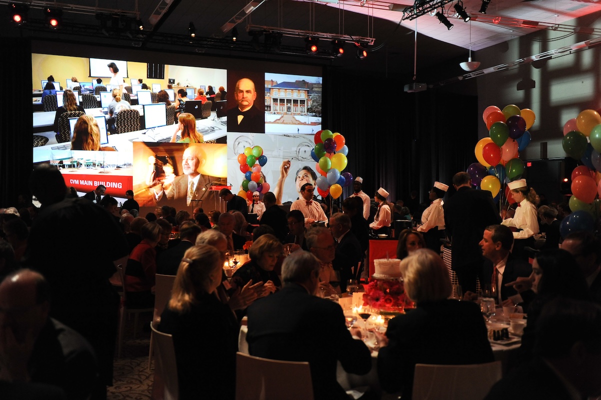 Founders' Day Dinner attendees enjoying images highlighting the theme of Tradition + Transformation