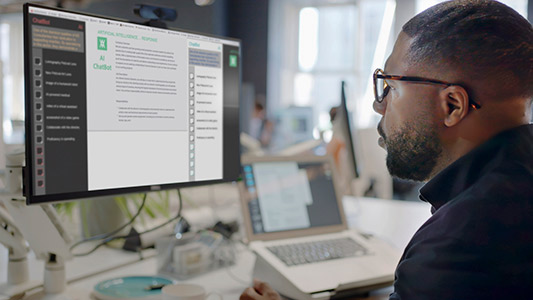 A man at computer using Artificial Intelligence, AI, chatbot in an office setting.