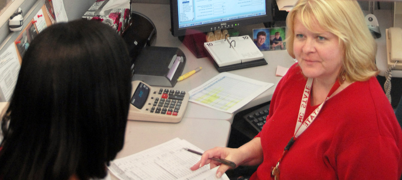 Financial staff member in office talking to colleague at NC State